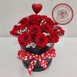 Red roses in a black hatbox with a heart topper and red ribbon