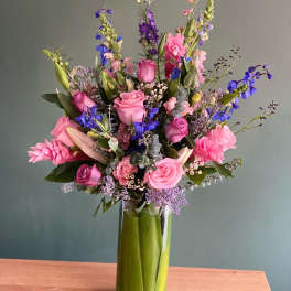 Pink and purple mixed flower arrangement in a tall glass vase