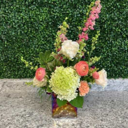 Mixed bouquet in a square glass vase with pink, white, and green blooms