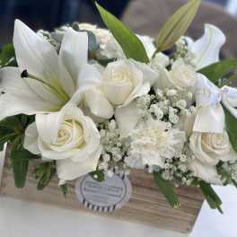 White roses and lilies arranged in a wooden box