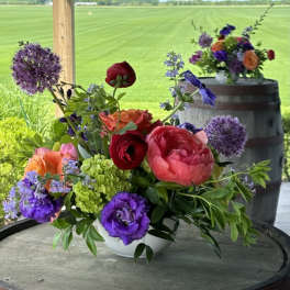 Colorful mixed flower arrangement in a white bowl on a round table
