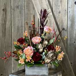 Mixed floral arrangement in a gray wooden box with burgundy and peach blooms