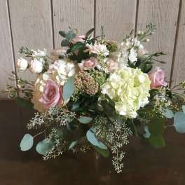 Low floral arrangement with pink roses, white hydrangeas, and greenery
