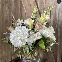 White hydrangeas and lilies with pale pink roses in a glass vase