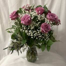 Bouquet of lavender roses and white baby's breath in a glass vase
