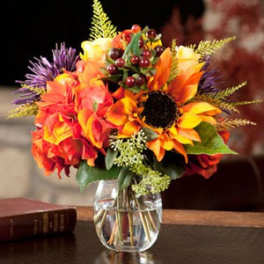 Bright autumn bouquet with sunflowers and orange flowers in a glass vase