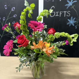Mixed bouquet with roses, gerbera daisies, and orange alstroemeria in a glass vase