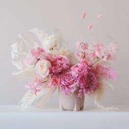 Pink and white floral arrangement in a pale vase