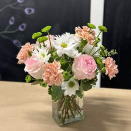 Pink and white flowers arranged in a clear glass vase