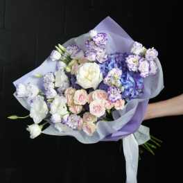 Hand-tied bouquet of purple, white, and pink flowers wrapped in lavender paper