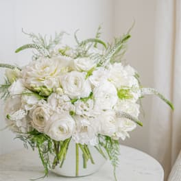 White floral bouquet in a clear glass vase on a round table
