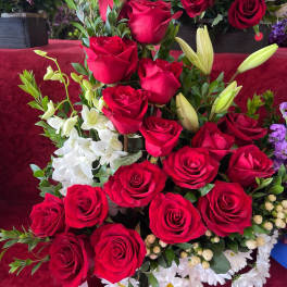 Tall arrangement of red roses with white lilies and daisies