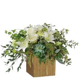White roses and lilies in a wooden cube vase with trailing greenery