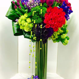 Tall bouquet of multicolored flowers in a glass vase with hanging beads