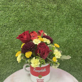 Bouquet of red, yellow, and cream flowers in a Campbell's soup mug