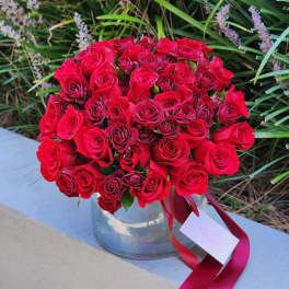 Bouquet of red roses in a clear glass vase with a ribbon tag