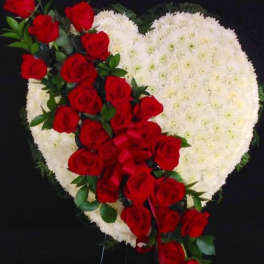 Heart-shaped white floral spray with red roses and ribbon