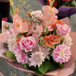 Pink and orange mixed bouquet with roses and daisies wrapped in pink paper