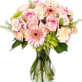 Bouquet of pink roses, gerbera daisies, and cream blooms with green hydrangea in a clear glass vase
