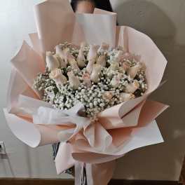 Bouquet of pale pink roses and white baby's breath wrapped in blush paper