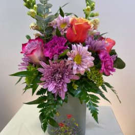 Mixed bouquet of pink and orange flowers in a gray vase
