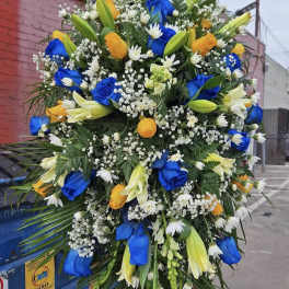 Large standing floral spray with blue and yellow roses and white lilies