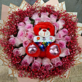Pink rose bouquet with a red teddy bear in the center