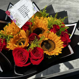 Bouquet of red roses and sunflowers with a birthday card
