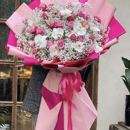 Large bouquet of pink roses and white orchids wrapped in pink paper
