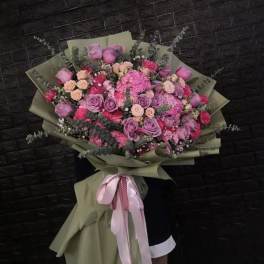 Large bouquet of pink and purple roses wrapped in olive paper