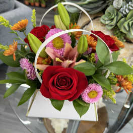 Red roses and pink daisies in a white handled box