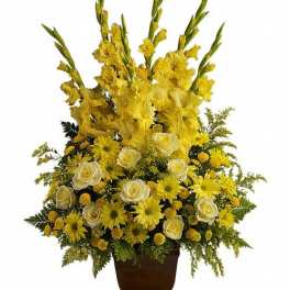 Tall yellow and white flower arrangement with gladiolus, roses, and daisies in a brown vase