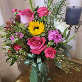Bouquet of pink roses, carnations, and a sunflower with a ribbon tie