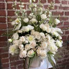 White floral arrangement in a round vase with roses and daisies
