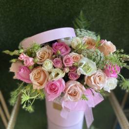 Pink and peach roses arranged in a pale pink hatbox