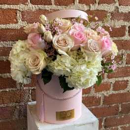 Pink and cream roses with white hydrangeas in a pink hatbox