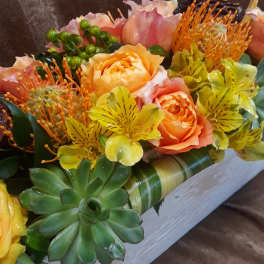 Bouquet of peach roses, yellow alstroemeria, and succulents in a white box