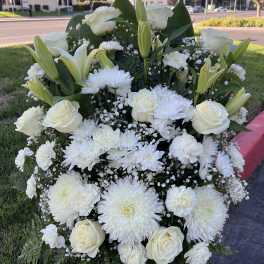 Large white floral standing spray with roses, lilies, and chrysanthemums