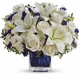 White lilies and roses arranged in a blue glass vase