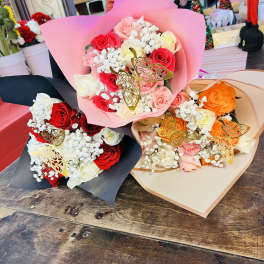 Three rose bouquets wrapped in pink, black, and beige paper