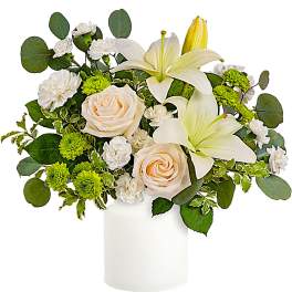 White lilies and cream roses in a white vase with green accents