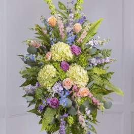 Tall floral standing spray with pastel roses, hydrangeas, and purple blooms