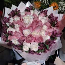 Bouquet of pink and white roses with purple flowers wrapped in pale paper
