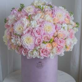 Round pastel bouquet of pink and white roses in a lavender box