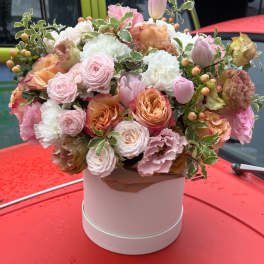 Pastel bouquet of roses, tulips, and carnations in a pink hat box