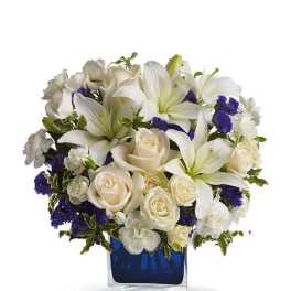 White lilies and cream roses arranged in a blue glass vase