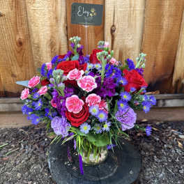 Mixed bouquet of red, pink, and purple flowers in a glass vase