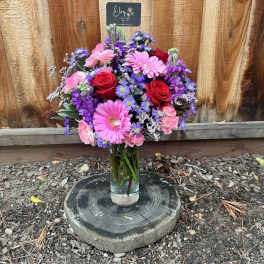 Mixed bouquet of pink, red, and purple flowers in a glass vase
