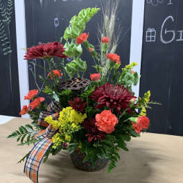 Mixed floral arrangement in a decorative vase with a plaid ribbon