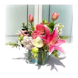 Pink lilies and roses in a glass vase with mixed blooms